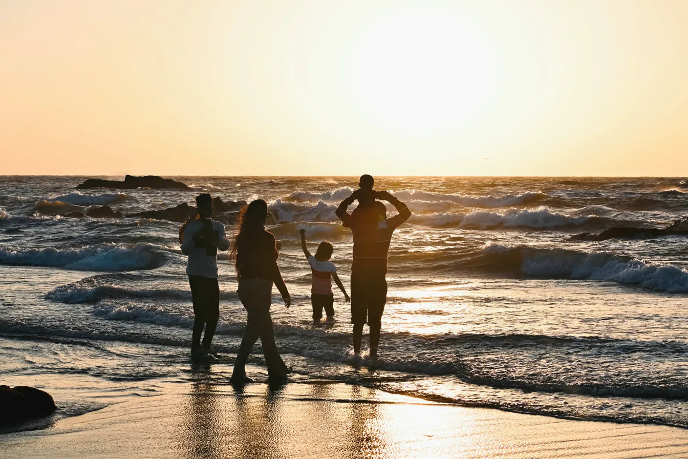 Famille profitant du coucher de soleil sur une plage du Bassin d'Arcachon grâce au service de location Bébé Nomad.